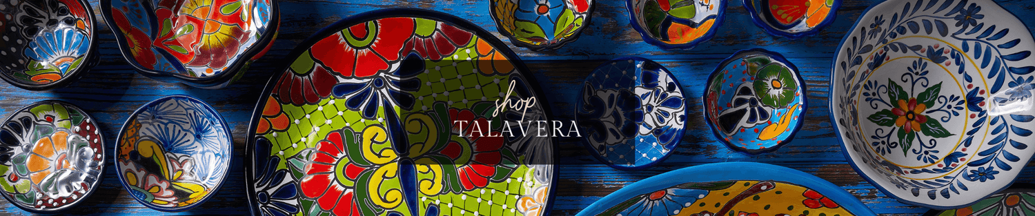 Colorful hand-painted Talavera ceramic bowls and plates arranged on a blue wooden table, showcasing vibrant floral and geometric patterns