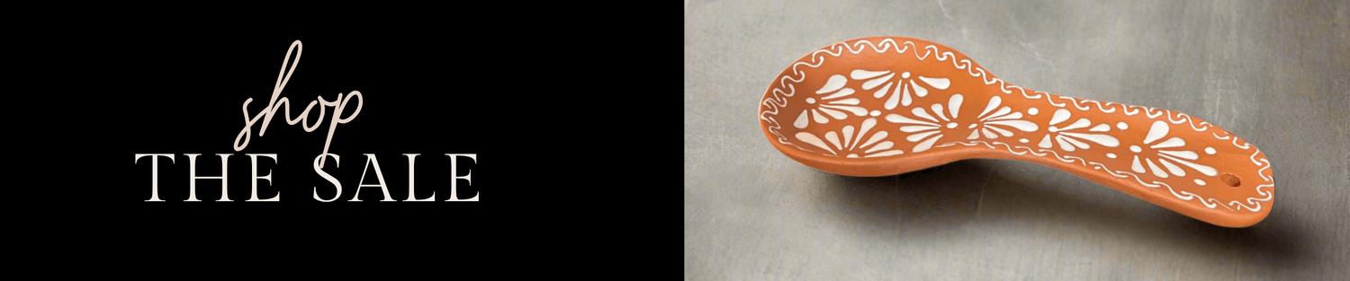 hand-painted terracotta ceramic spoon rest with white floral pattern on gray background