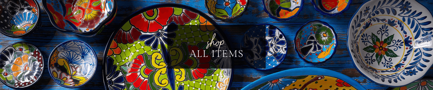 Colorful hand-painted ceramic bowls and plates arranged on a dark blue wooden surface — vibrant patterns for home decor and tableware