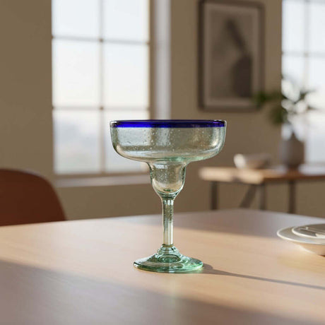 The Talavera Hub Hand-Blown Margarita Glass with cobalt blue rim and clear, green-tinted recycled glass body. 16oz capacity.