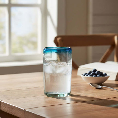 The Talavera Hub Hand-Blown Mexican Tumbler Glass with clear body and teal rim. 5" tall, made from recycled glass.