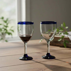 The Talavera Hub hand-blown Mexican wine glass with clear bowl, cobalt blue rim, and dark blue base. Holds 12 oz.