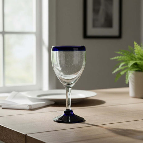 The Talavera Hub hand-blown Mexican wine glass with a clear bowl, cobalt blue rim, and black base. Holds 12 oz.