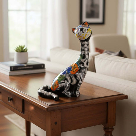 The Talavera Hub hand-painted ceramic cat figurine with Day of the Dead design, featuring floral motifs in orange, blue, and green.