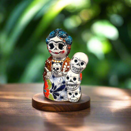 Handcrafted Talavera Frida Statue | Colorful Day of the Dead Calavera Skull Decor — hand-painted Mexican Talavera Frida with stacked skulls on wooden base
