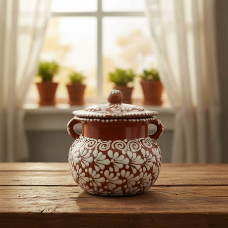 The Talavera Hub brown and white glazed ceramic bean pot with lid, featuring a floral design and dual handles.