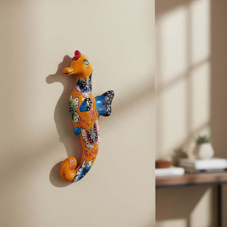The Talavera Hub orange ceramic seahorse figurine with hand-painted butterflies and floral motifs in blue, pink, and green.