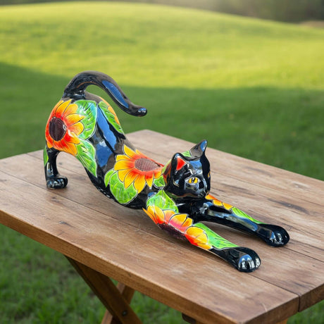 The Talavera Hub black ceramic cat statue with hand-painted sunflower design, stretching pose.