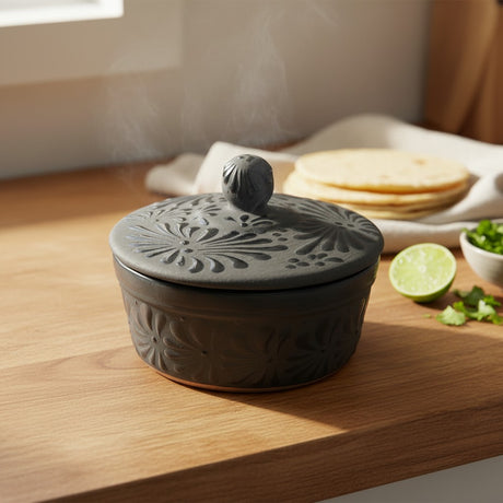 The Talavera Hub black ceramic tortilla keeper with carved floral motifs and a decorative knob on the lid.