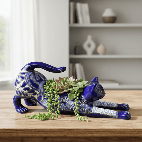 The Talavera Hub hand-painted blue Talavera cat planter with white floral accents, in a stretching pose.
