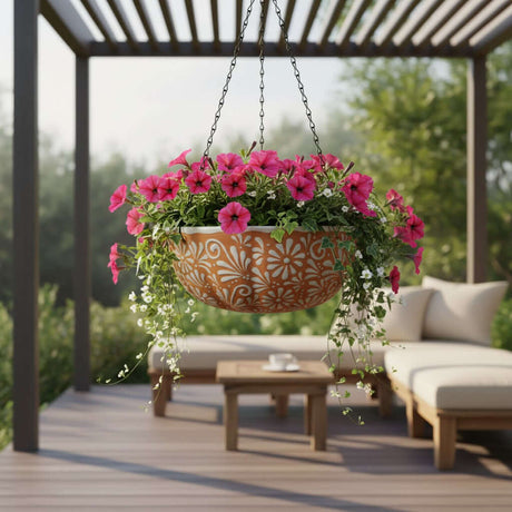 The Talavera Hub brown and white ceramic hanging planter with intricate floral motifs, filled with vibrant pink flowers.