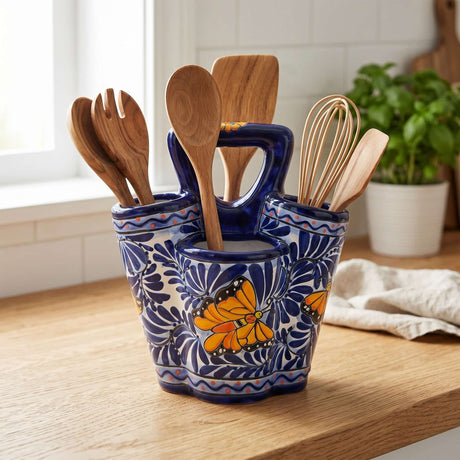 The Talavera Hub handmade ceramic utensil holder in blue and white with hand-painted butterfly motifs on a wooden counter.
