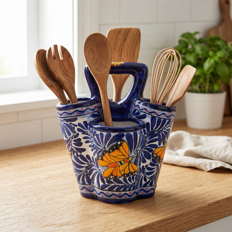 The Talavera Hub handmade ceramic utensil holder in blue and white with hand-painted butterfly motifs on a wooden counter.