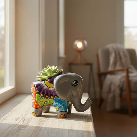 The Talavera Hub hand-painted ceramic elephant planter with colorful floral patterns holding a small green succulent.