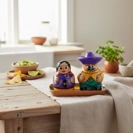 The Talavera Hub hand-painted ceramic salt and pepper shakers featuring a couple on a tray in vibrant folk colors.
