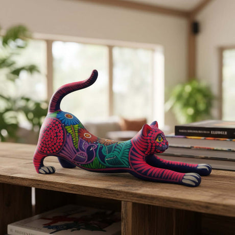 The Talavera Hub handcrafted ceramic stretching cat figurine with vibrant Mexican folk art patterns on a wooden shelf.