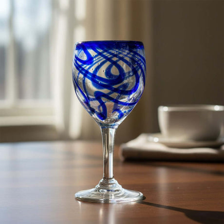 The Talavera Hub hand-blown cobalt blue swirl wine glass. Clear glass goblet with a classic silhouette and sturdy stem.