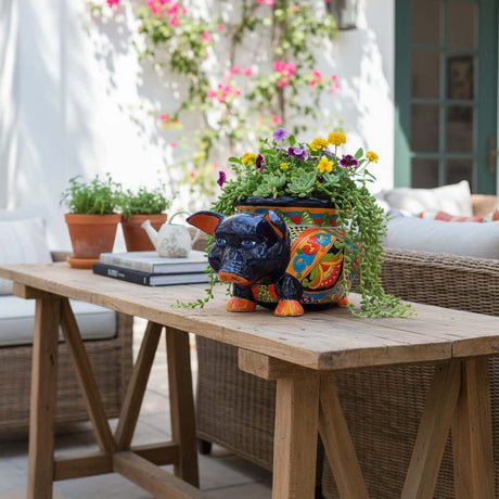 The Talavera Hub hand-painted ceramic pig planter with colorful floral and geometric patterns, blue eyes, and orange hooves.