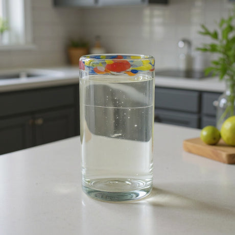 The Talavera Hub hand-blown glass tumbler with a clear body and a colorful confetti rim. Ideal for everyday use or festive occasions.