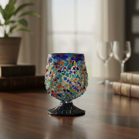 The Talavera Hub colorful confetti rock shot glass with blue rim and pedestal base, hand-blown recycled glass.