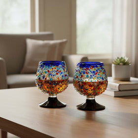 The Talavera Hub confetti rock shot glass with blue rim and pedestal base, made of lead-free glass.