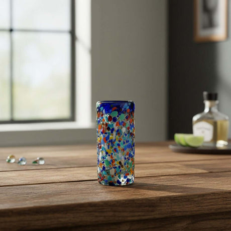 The Talavera Hub hand-blown glass double shot glass with multicolor confetti accents and blue rim.