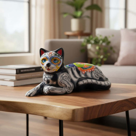 The Talavera Hub black ceramic cat statue with Day of the Dead painted details in orange, green, white, and red.