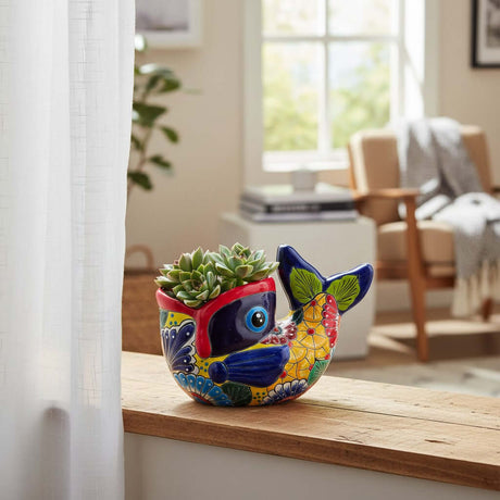 The Talavera Hub hand-painted ceramic fish planter in vibrant red, yellow, and blue with floral motifs holding a succulent