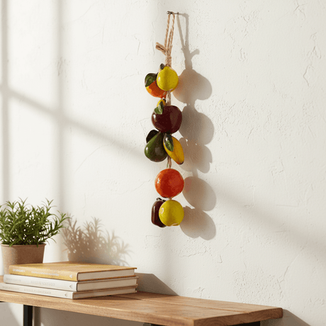 The Talavera Hub hand-painted ceramic fruit garland featuring apples, oranges, and pears in vibrant colors, strung on twine.
