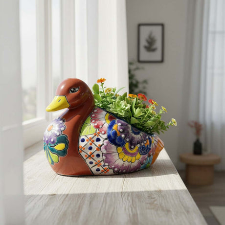 The Talavera Hub handmade Mexican ceramic duck planter with vibrant floral folk art patterns holding small succulents.