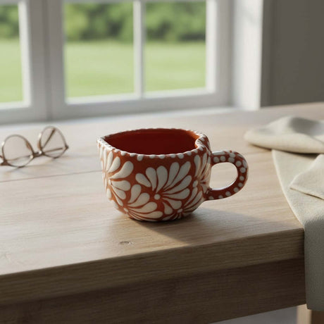 The Talavera Hub hand-painted ceramic mug with a heart motif in orange and white floral design. Mexican coffee cup.