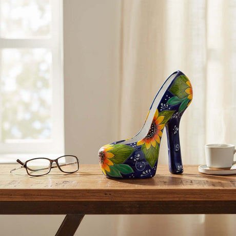 The Talavera Hub handcrafted ceramic high heel statue with blue background and vibrant yellow sunflower motif