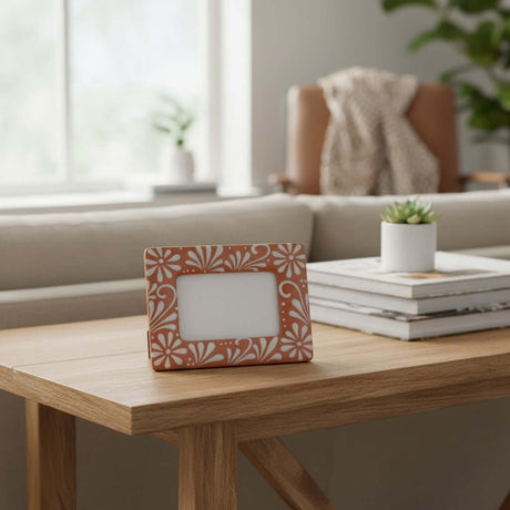 The Talavera Hub handmade terracotta photo frame with white floral patterns displayed on a wooden console table.