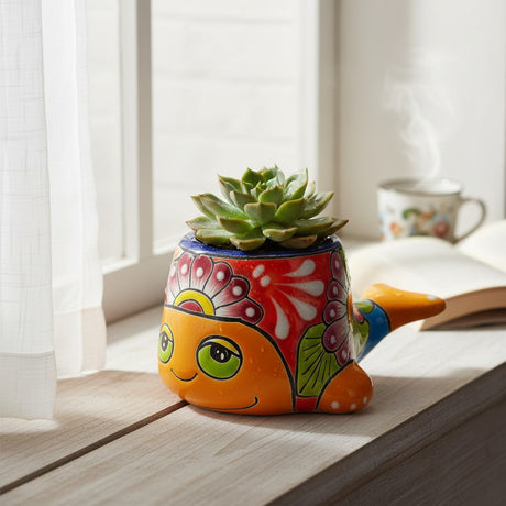 The Talavera Hub small whale planter with vibrant hand-painted floral patterns in orange, red, and blue on a windowsill
