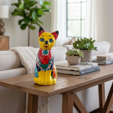 The Talavera Hub yellow ceramic cat statue with blue eyes, red ears, and colorful floral patterns. Mexican folk art decor.