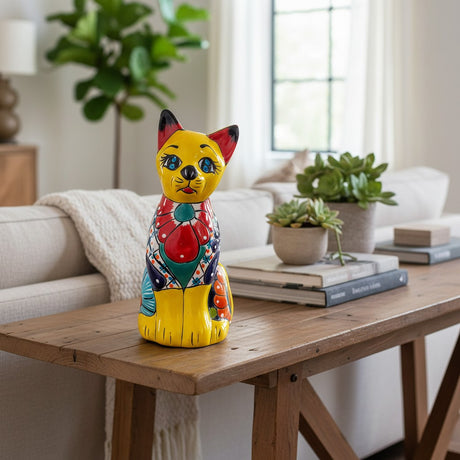 The Talavera Hub yellow ceramic cat statue with blue eyes, red ears, and colorful floral patterns. Mexican folk art decor.