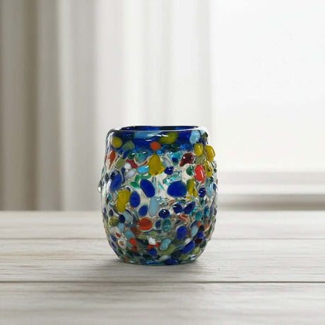 The Talavera Hub Confetti Rimmed Shot Glass with blue rim and multicolor glass flecks. Hand-blown recycled glass.