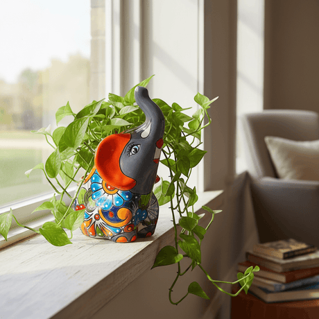 The Talavera Hub handmade gray elephant planter with colorful floral Talavera design and orange accents.