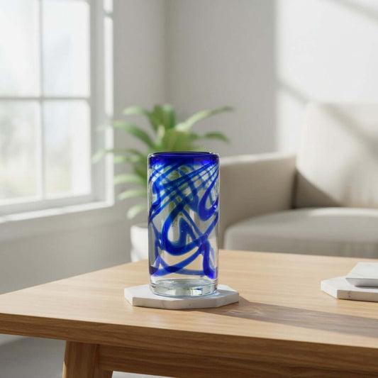 Tall clear drinking glass with blue swirl decoration on a table
