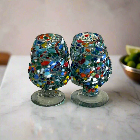 Confetti Rock Shot Glass | Handcrafted Mexican Cognac-Style Glass - pair of hand-blown, colorfully beaded mini goblet shot glasses on marble surface