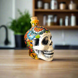 Talavera Skull Decanter | Small Day of the Dead Ceramic Bottle hand-painted Talavera skull decanter on tabletop, colorful Día de los Muertos design