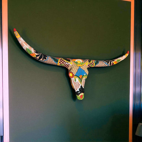 Talavera Longhorn Skull | Handmade Mexican Bull Wall Art hand-painted colorful Talavera bull skull on green wall, kiln-fired, terracotta base