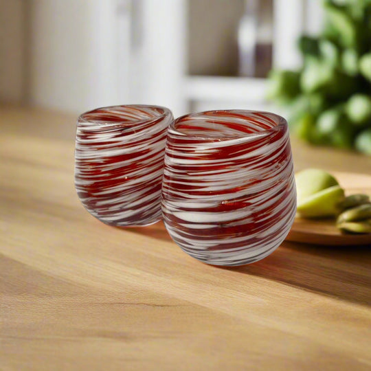 Red Swirl Stemless Wine Glass | Hand-Blown Mexican Glassware - pair of hand-blown red and white swirl stemless wine glasses on wooden table