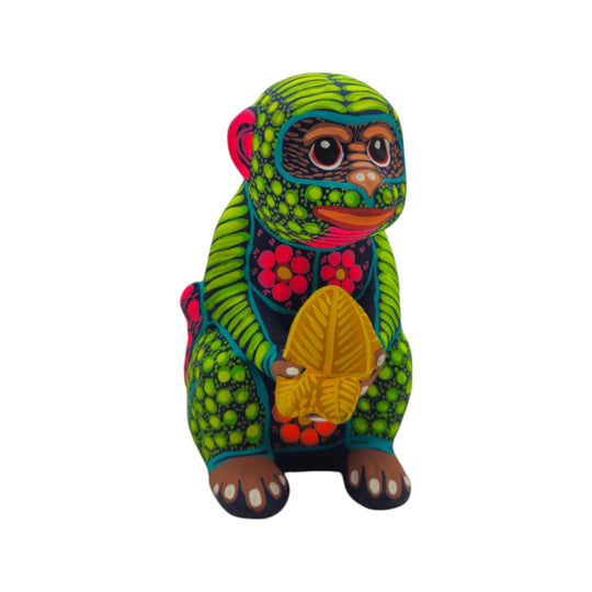 Front view of a green and multicolor Alebrije monkey figurine holding a butterfly