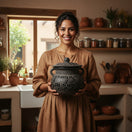 Black Talavera Bean Pot with Lid | Mexican Clay Frijolero held by smiling woman in rustic kitchen, hand-painted black-on-black carved floral design