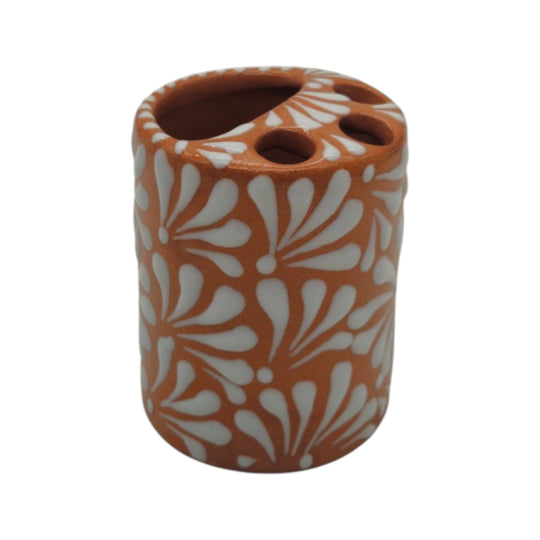 Side view of brown and white Talavera toothbrush holder with white floral motifs