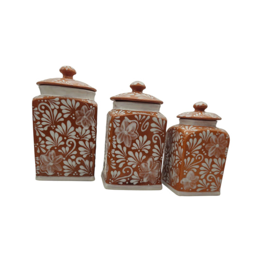 Grouped brown and white floral Talavera canisters on a white background