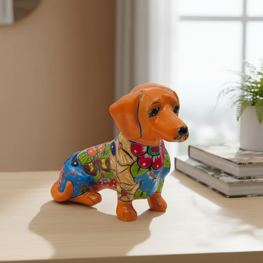 The Talavera Hub orange ceramic dachshund figurine with colorful floral patterns. Handcrafted Mexican Talavera art.