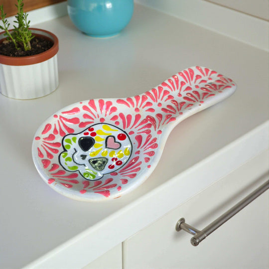 Colorful Talavera Skull Spoon Rest | Mexican Kitchen Art - hand-painted pink floral skull ceramic spoon rest on white countertop