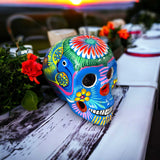 Guerrero Calavera Skull | Large Hand-Painted Day of the Dead Art - vibrant hand-painted Guerrero pottery skull on table at sunset